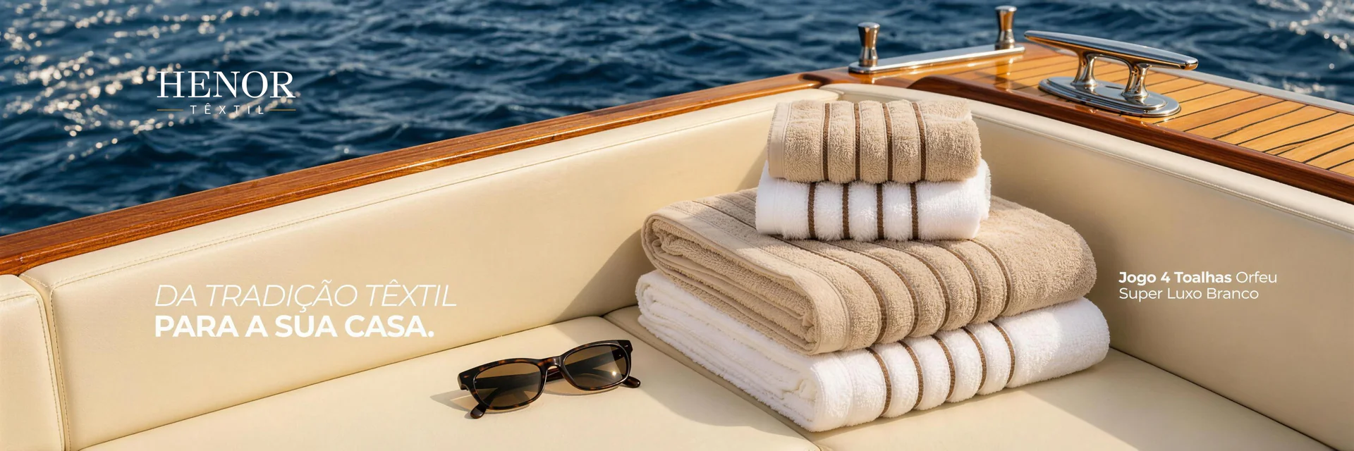Banner Henor Têxtil: jogo de toalhas Orfeu Super Luxo no convés de um barco — da tradição têxtil para a sua casa
